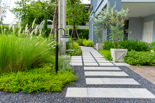 Modern design home garden landscaping. Flower garden and green plant with brick border and pedestrian pathway.