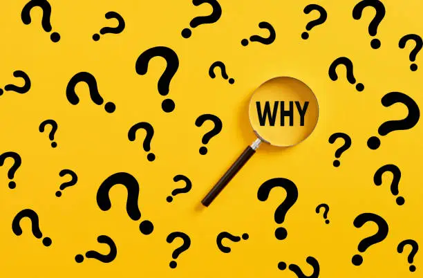 Photo of Searching for information, data, solution or answer. Magnifying glass magnifies the word why and question mark signs on yellow background.