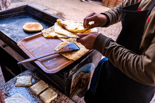 Marrakech, Morocco; 15th december 2022: A person prepares some bread cakes in the street. Street food stalls are very popular in Moroccan cities.