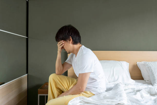 istock Depressed Asian man sitting in bed cannot sleep. 1455232241
