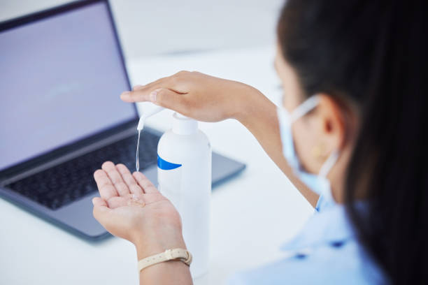 Covid, hand sanitizer and a woman with laptop and face mask in office. Online work, hygiene and a businesswoman with alcohol spray on hands at desk. Safety, working and cleaning hands during pandemic covid, desinfectante de manos y una mujer con computadora portátil y máscara facial en la oficina. trabajo en línea, higiene y una mujer de negocios con alcohol en aerosol en las manos en el escritorio. seguridad, trabajo y limpieza de manos durante la