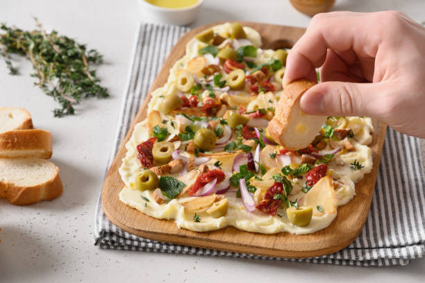 istock Men hand spreads bread with cheese from butter board. Close up 1455234510