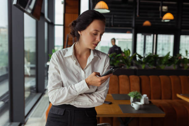 istock Young businesswoman using mobile phone in cafe 1455234623