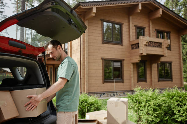istock Man unloading boxes from car trunk while moving into new wooden house in nature 1455235429