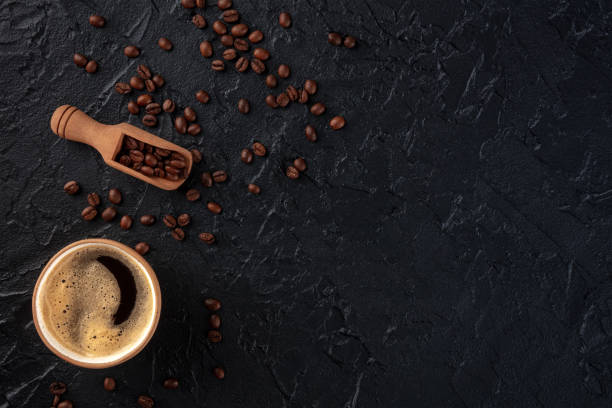 Coffee cup and beans, shot from the top on a black slate background stock photo