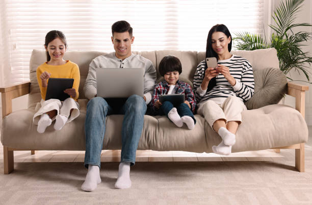 istock Internet addiction. Family with different gadgets on sofa at home 1455239514