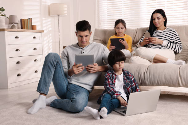 インターネット中毒。リビングルームにさまざまなガジェットを持つ家族 - family room ストックフォトと画像