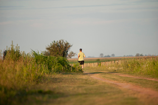 Firmat, Argentina – February 13, 2021: A lonely male runner on a rural dirt road in Firmat, Argentina