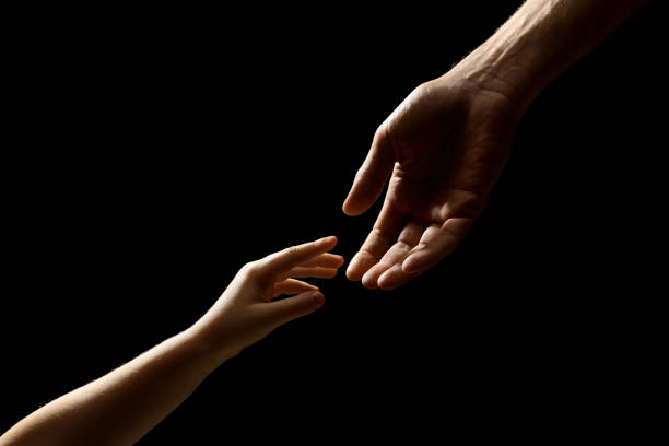 istock Man with child on black background, closeup of hands 1455242112