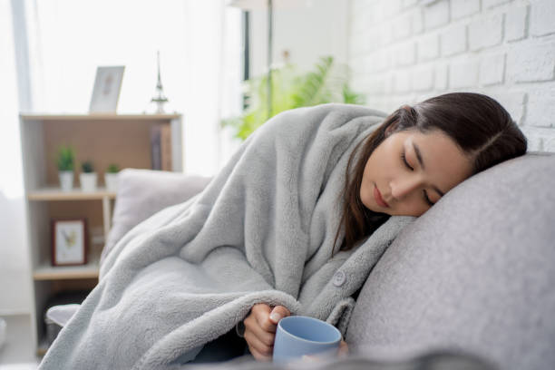 istock Feeling sick. Sick young women covered with blanket resting at home while sitting on the sofa 1455242149
