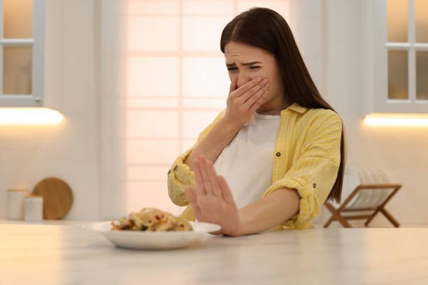 istock Young woman feeling nausea while seeing food at table in kitchen 1455242670