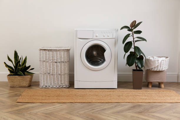 istock Laundry room interior with modern washing machine and wicker basket near white wall 1455242802