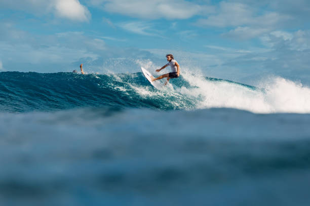 4 stycznia 2023 r. bali, indonezja. człowiek w tropikalnym oceanie podczas surfowania. surfer jeździ na desce surfingowej na niebieskiej fali. - co surfing zdjęcia i obrazy z banku zdjęć