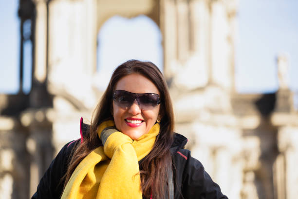 Frontal portrait of a latin lady while she is outside in a cold winter day. She is smiling to the camera and is wearing winter clothes