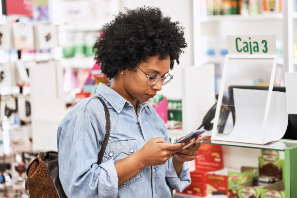 istock African woman customer using mobile phone in pharmacy 1455245461