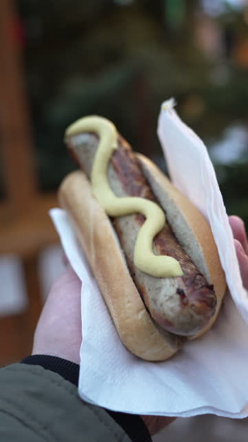 Unrecognizable man holding bun with sausage, at the Christmas market