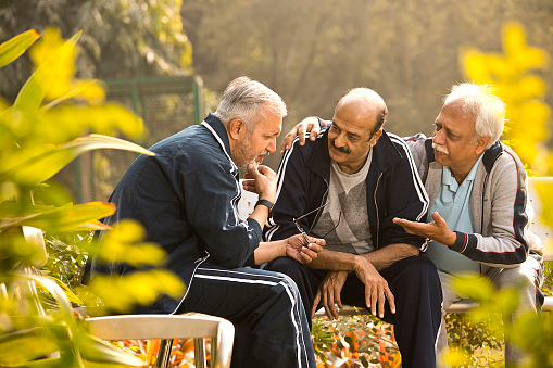 Men comforting and giving moral support to senior friend suffering with depression at park