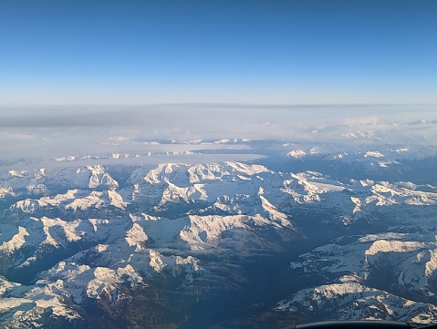Panoramic view from an airplane high above the clouds over the snowy Alps