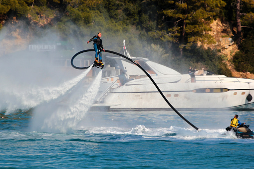 Kemer, Turkey - January 8, 2023: Tourists playing flyboard, a hydroflighting device which supplies propulsion to drive the Flyboard into the air to perform a sport known as hydroflying.