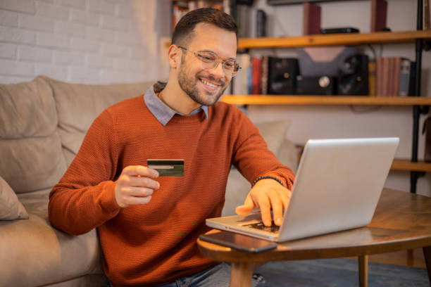istock Cheerful man doing online shopping 1455248761