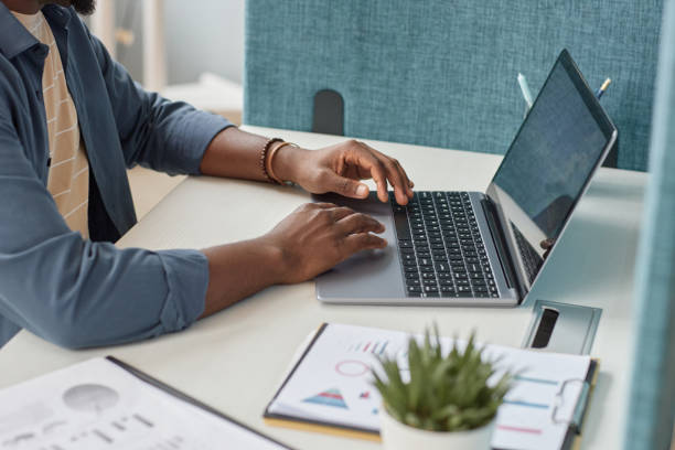 Close up of unrecognizable black man typing at laptop keyboard