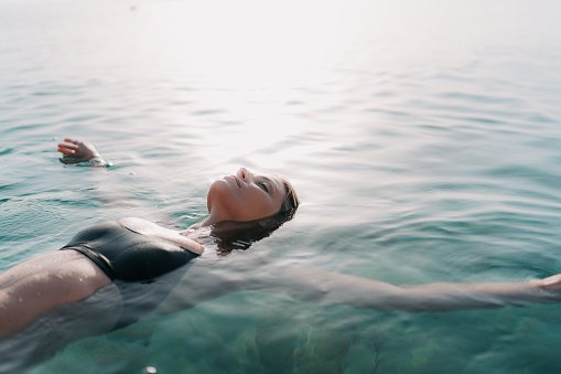 Photo of a young woman relaxing and cooling off in the ocean on a hot summer afternoon