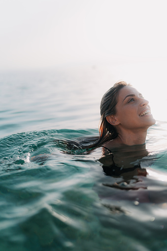 Photo of a young woman relaxing and cooling off in the sea on a hot summer afternoon
