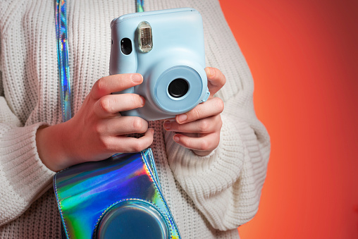 A teenage girl takes photos with a polaroid camera-studio shot