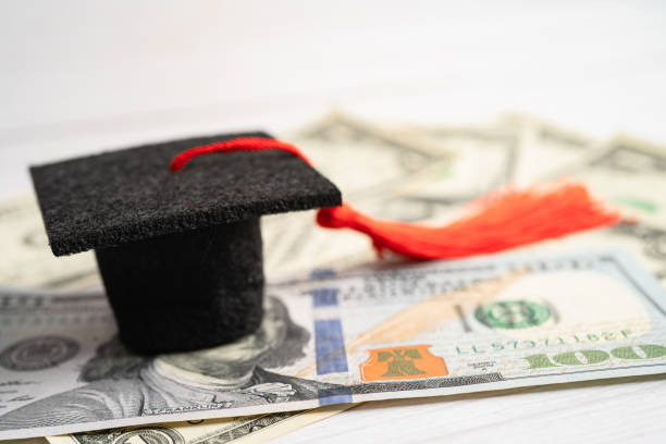 istock Graduation gap hat on US dollar banknotes money, Education study fee learning teach concept. 1455253679