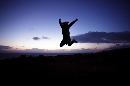 silhouette of friends jumping in sunset at beach