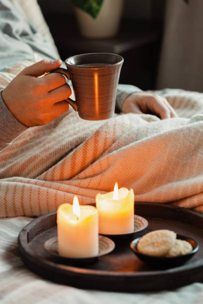istock A caucasian man relaxing at home, lighting candle, drinking coffee in bed under blanket 1455258815