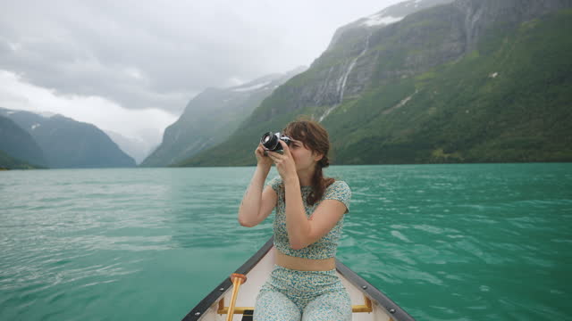 Woman photographing while canoeing on the lake in Norway