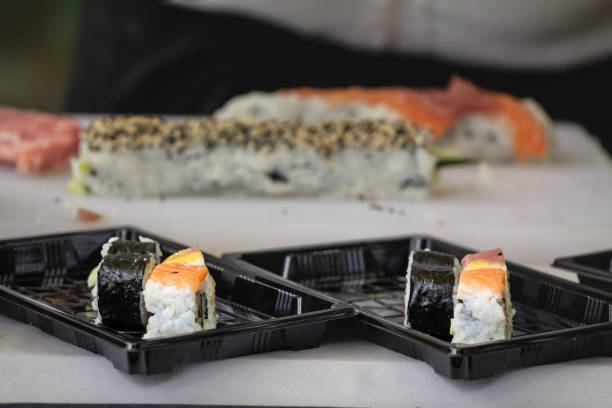 istock Selective blur on sushi and sashimi made of salmon and weed in plastic boxes getting prepared to be delivered in a sushi to go takeaway business. 1455260776