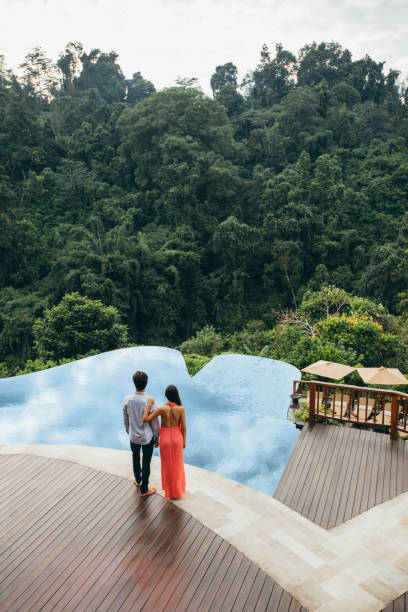 istock Young couple standing by a swimming pool 1455260937