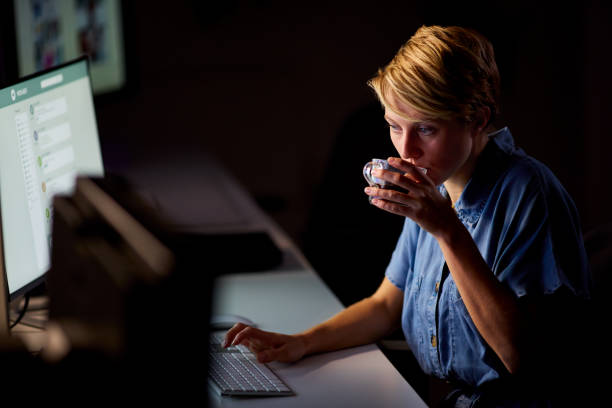 istock Businesswoman Working Late In Office With Face Illuminated By Computer Screen Drinking Coffee 1455261071