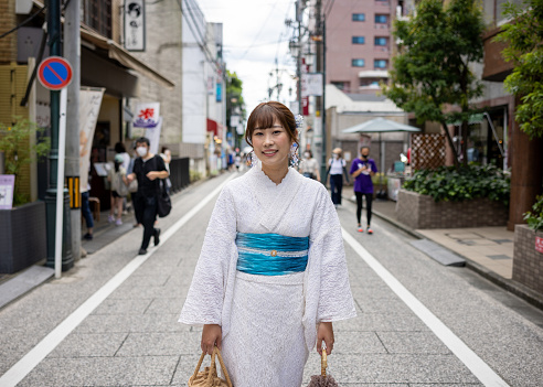 Portrait of woman in white lace kimono walking on street in traditional Japanese town for shopping