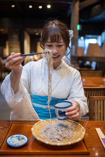 Japanese woman in summer lace kimono eating soba in Japanese restaurant