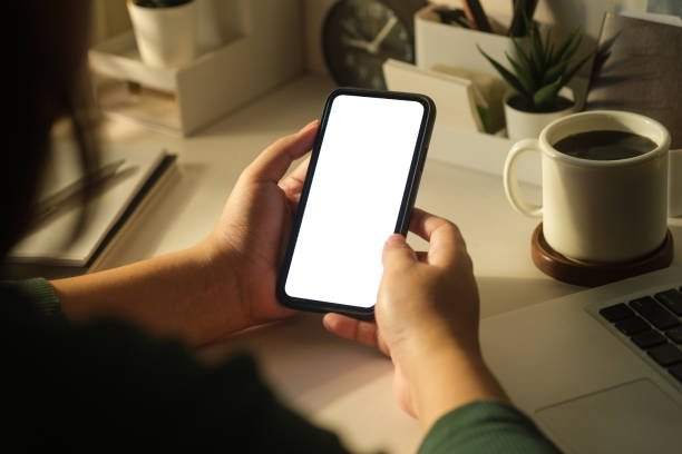 istock Over shoulder view of woman using mobile phone at her workplace. Blank screen for your advertise design. 1455264422