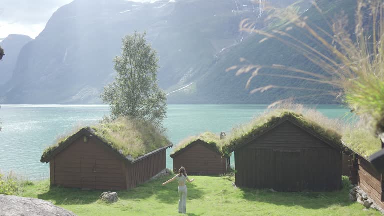 Woman near the huts in moss on the background of fjord