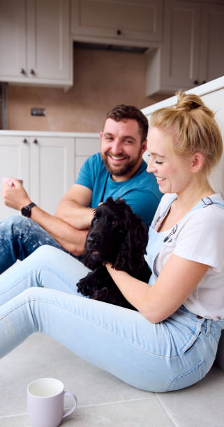 istock Couple On Coffee Break From Renovating Kitchen At Home Playing With Pet Spaniel Dog 1455265447