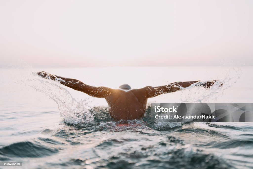 Determined athlete's swim training Photo of a young man who is having daily swim training in the sea Swimming Stock Photo