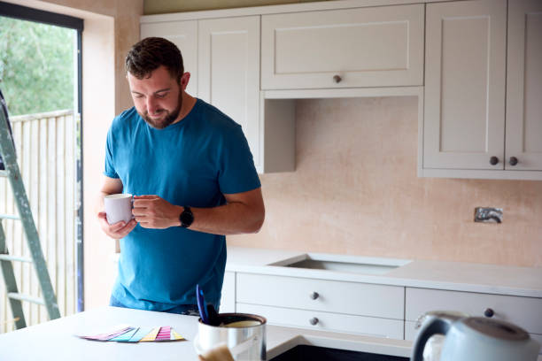 istock Man Renovating Kitchen At Home Looking At Paint Swatches On Coffee Break 1455265709
