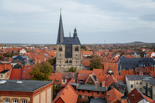 Quedlinburg, Saxony-Anhalt, Germany, 28 October 2022: Panoramic view of city from observation platform, old houses with red tiled roofs, tower and spire of St. Benedict church, sunny autumn day
