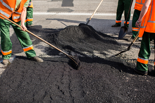 Road worker uses a portable asphalt cutter to cut worn asphalt with a diamond blade to repair part of the roadway