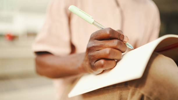 istock Close-up of young african student's hand taking notes 1455273068