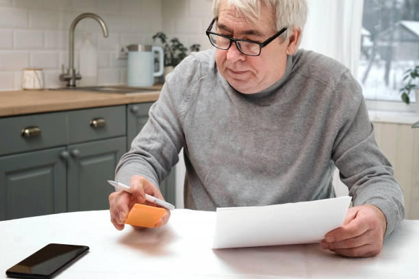 Senior Man Checking Calculating Personal Finance at Home, Feeling Stress from Money Problem. Concerned Elderly Male get Official Bank Notification, Financial Bill, Unpaid Debt or Tax and Feel Worried. overwhelmed Upset retired pensioner using calculator. utility bill hombre mayor que verifica el cálculo de las finanzas personales en el hogar, sintiendo estrés por el problema del dinero. hombre anciano preocupado recibe notificación bancaria oficial, factura financiera, deuda impaga o impuestos y se siente preocupado