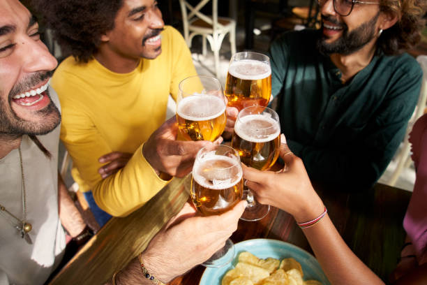 Group of colleague workers toast with beer in the restaurant bar after work at the pub happy hour stock photo