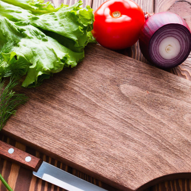 istock Fresh vegetables next to a cutting board on a wooden background 1455279750