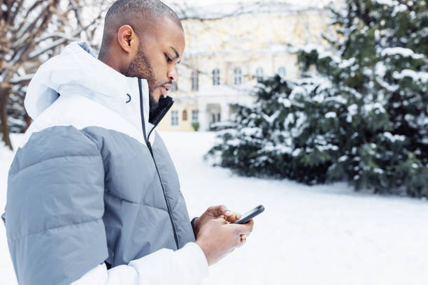 istock Young African man typing message, texting on phone, winter outdoor 1455283497