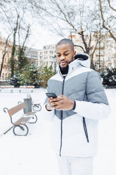 istock Young African man typing message, texting on phone, winter outdoor 1455283510
